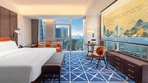 A hotel room with a large bed, a desk, a chair, and a view of the cityscape through large windows. - Grand Skylight International Hotel Jinan (Jinan)