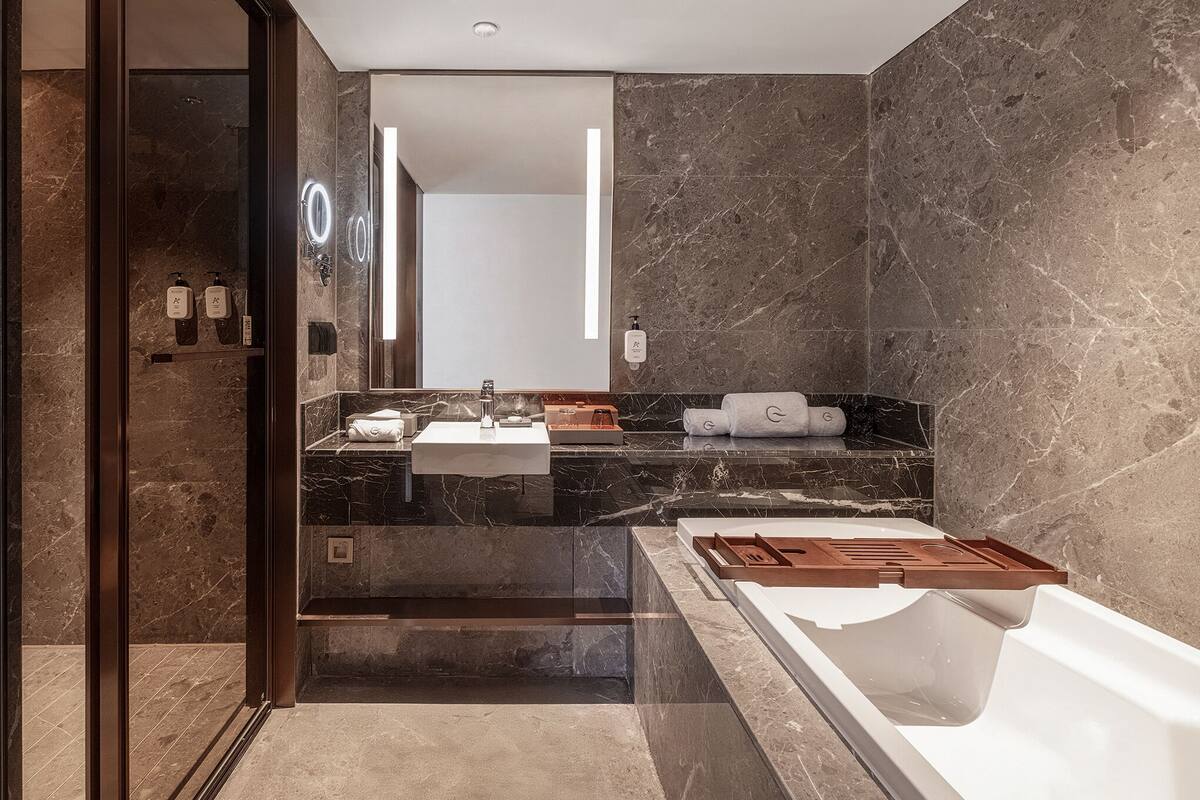 Un bagno moderno con un grande specchio, due lavabi, una vasca e pareti in marmo.