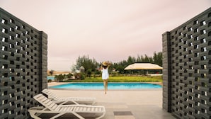 Ett område vid poolen med solstolar och en person som står vid poolkanten.