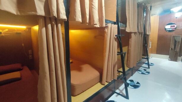 A bunk bed room with curtains, a bed, and a sign for 'Capsotel'. - Capsutel (Baguio)