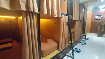 Habitación con literas, cortinas y un cartel que dice 'Capsotel'.