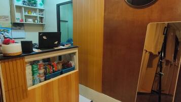 Un mostrador de recepción de hotel con una computadora, un espejo y un letrero que dice 'CAPSULE'.