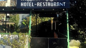 Une enseigne pour l’hôtel-restaurant VIP Papilat, offrant une vue dégagée sur l’entrée et la végétation environnante.