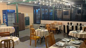 A dining area with tables set for meals, a Pepsi refrigerator, and a view through the windows. - Papillat Vip Llc (Batumi)