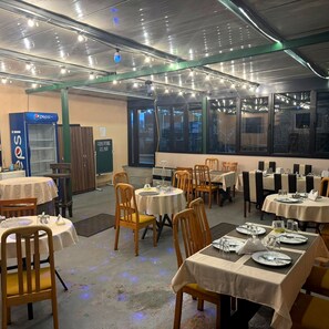 A dining area with tables set for meals, a Pepsi refrigerator, and a view through the windows. - Papillat Vip Llc (Batumi)