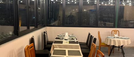 A dining area with a long table set for four, surrounded by chairs with yellow cushions.