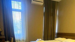 Une chambre d’hôtel équipée d’un lit, d’une chaise, d’un bureau et d’un appareil de climatisation.