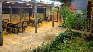 An outdoor patio area with a covered seating area, a dining table, and chairs. - Papillat Vip Llc (Batumi)