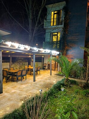 An outdoor patio area with a covered seating area, a dining table, and chairs. - Papillat Vip Llc (Batumi)
