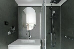 A modern bathroom with a white sink, a round mirror, and a shower with a handheld showerhead. - Royale Escale Torcy (Torcy)
