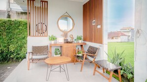 Eine Terrasse mit einem Holztisch, zwei Stühlen, einer kleinen Vitrine und einem Spiegel.
