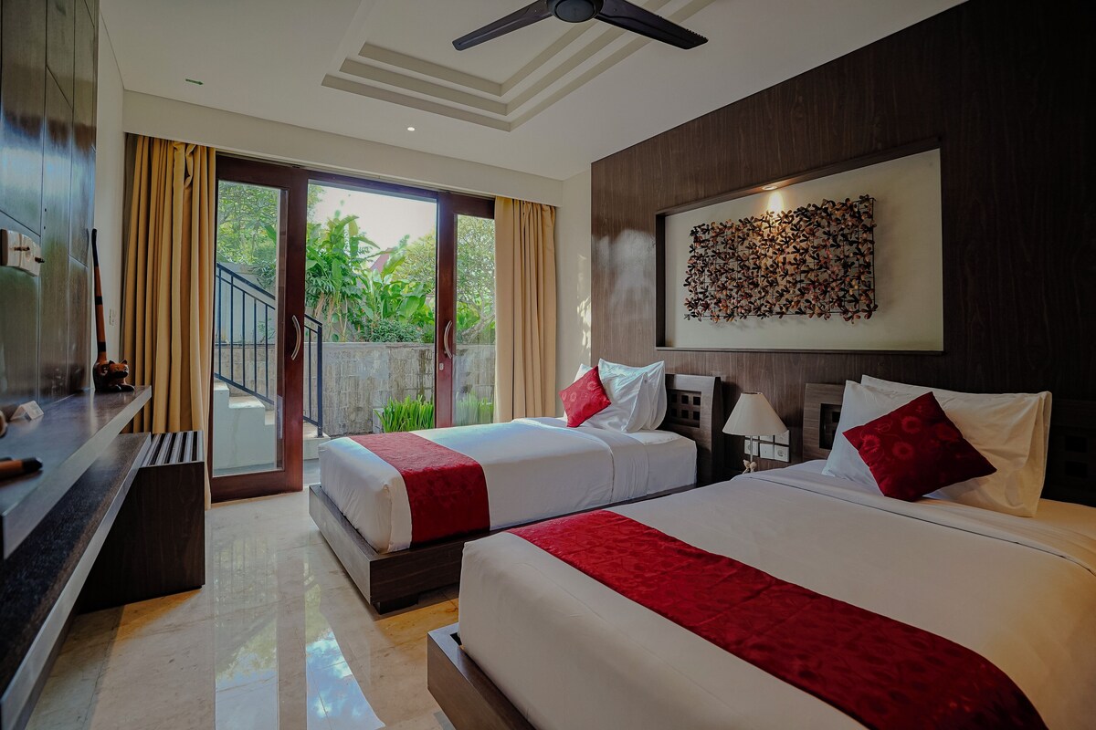 A hotel room with two beds, a balcony, a ceiling fan, and a wall-mounted artwork.