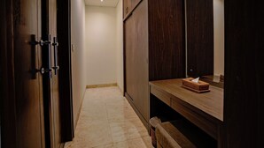 A hallway with a wooden door, a wooden vanity with a mirror, and a trash bin. - Campania Villa Bali (Sukawati)