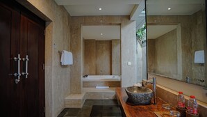 A modern bathroom with a wooden vanity, a large mirror, a stone sink, and a bathtub. - Campania Villa Bali (Sukawati)