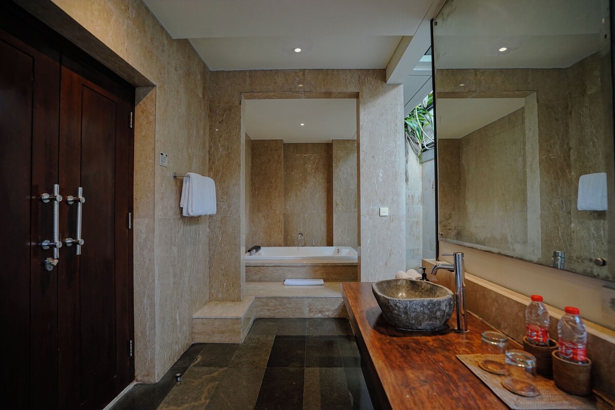A modern bathroom with a wooden vanity, a large mirror, a stone sink, and a bathtub.