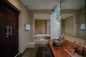 A modern bathroom with a wooden vanity, a large mirror, a stone sink, and a bathtub. - Campania Villa Bali (Sukawati)