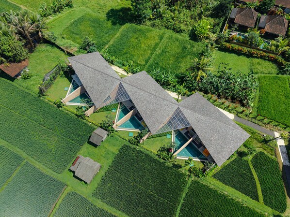 A modern resort with triangular roofs, a swimming pool, and lush green fields.