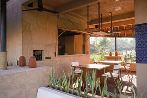 An outdoor dining area with a wooden table and chairs, a ceiling fan, and a view of the outdoors. - Terra Sayan (Ubud)