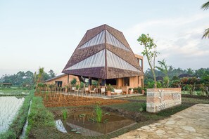 Ein pyramidenförmiges Gebäude mit einem Ziegeldach, umgeben von einem Garten und einem Wasserspeicher.