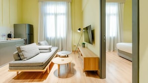 Una habitación de hotel moderna con sofá, una mesita redonda, televisión y cama.