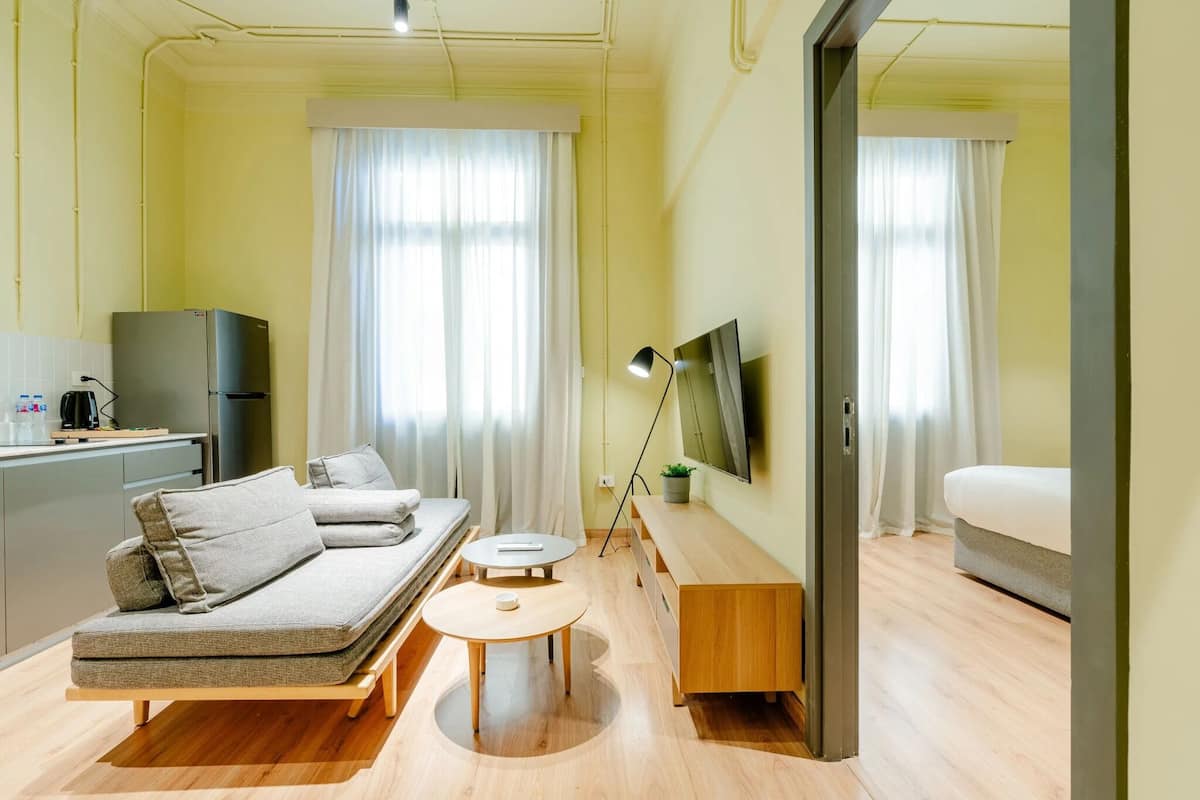 Une chambre d’hôtel moderne équipée d’un canapé, d’une petite table ronde, d’une télévision et d’un lit.