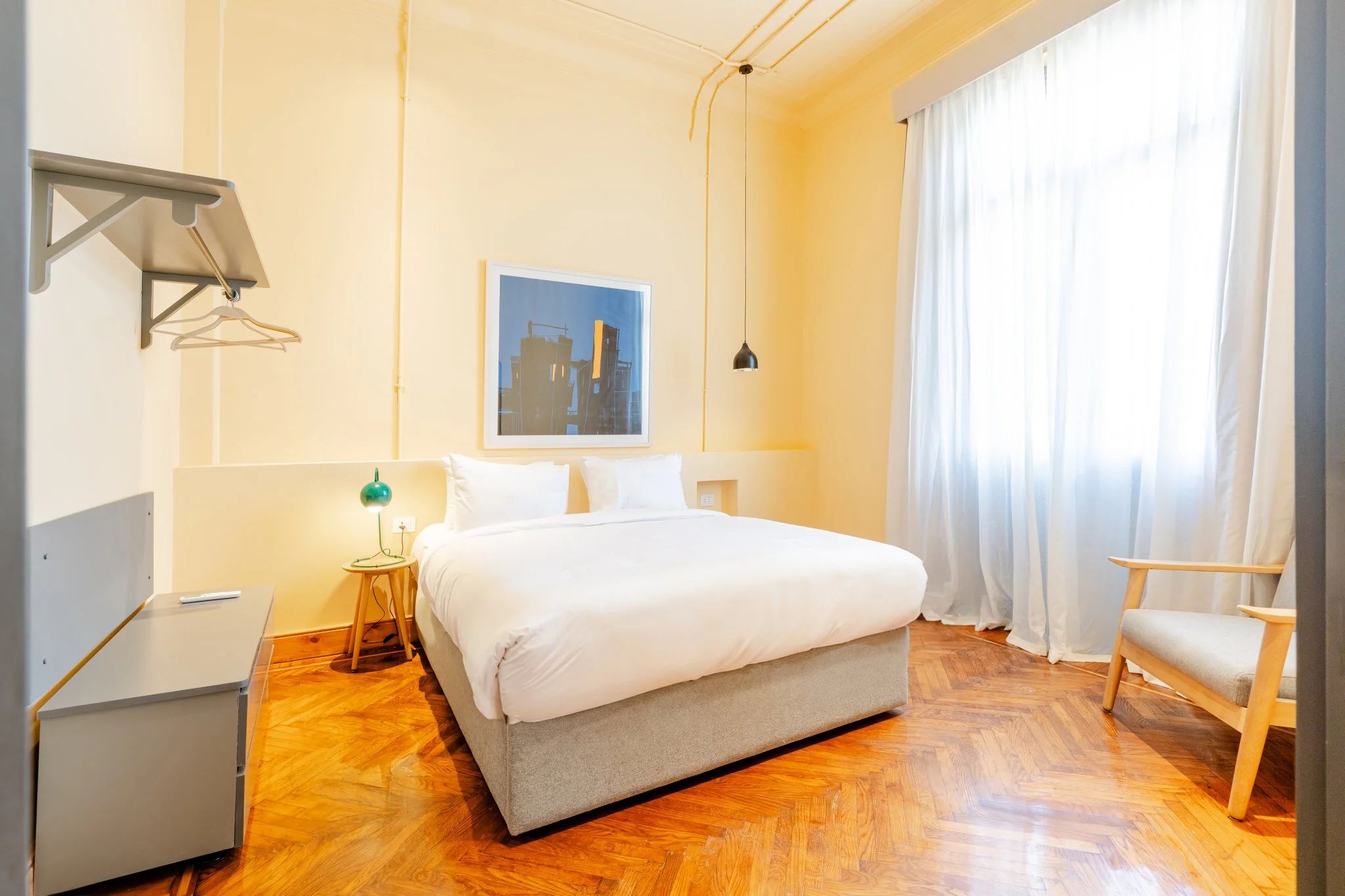 Una habitación de hotel con cama, mesita de noche, lámpara y una silla.