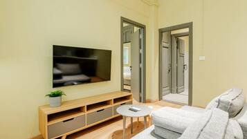 Een woonkamer met een televisie, een bank, een salontafel en een tv-meubel.