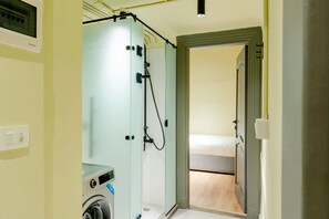 A compact hotel room with a washing machine, a shower area, and a bed. - Studio Apartments Downtown Alexandria Menascehouse (Alexandria)