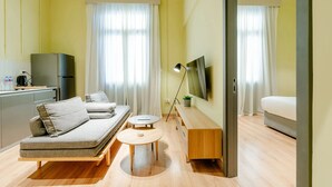 Une chambre d’hôtel moderne équipée d’un canapé, d’une petite table ronde, d’une télévision et d’un lit.