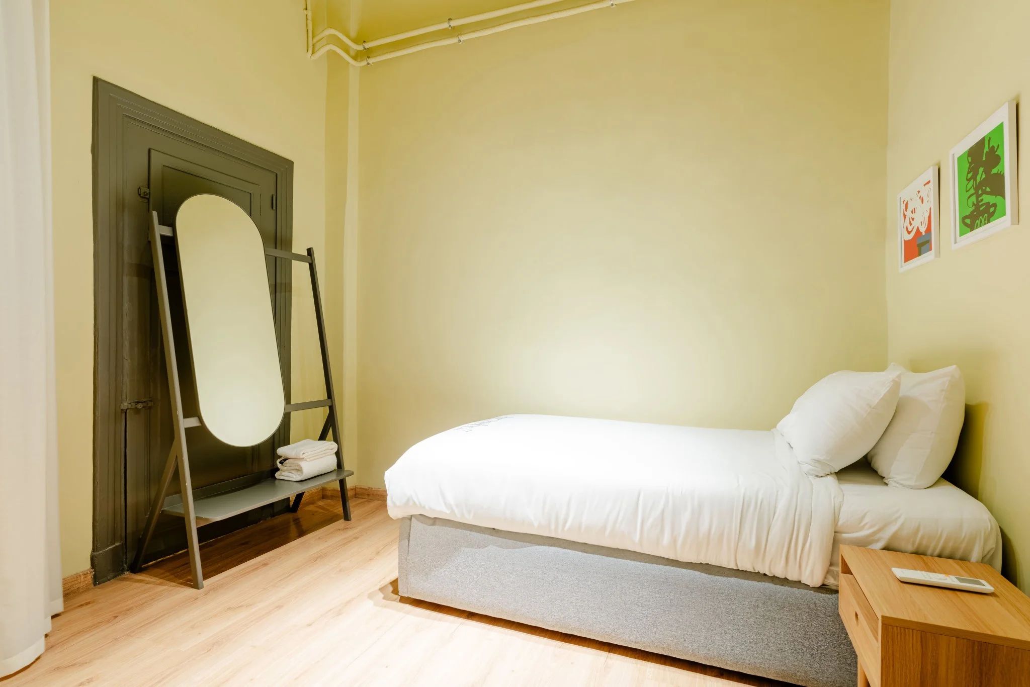 Un dormitorio con una cama, una mesita de noche de madera, un espejo y una puerta.