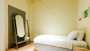 A bedroom with a bed, a wooden nightstand, a mirror, and a door. - Studio Apartments Downtown Alexandria Menascehouse (Alexandria)