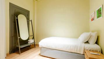 Un dormitorio con una cama, una mesita de noche de madera, un espejo y una puerta.