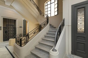 A marble staircase with black railings and a dark door with patterned glass panels. - Studio Apartments Downtown Alexandria Menascehouse (Alexandria)