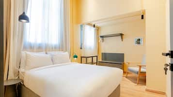Una habitación de hotel con una cama, televisión, silla y escritorio.