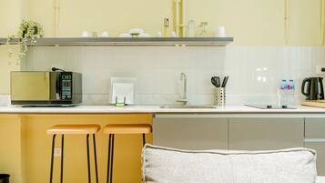 A modern kitchen with a microwave, coffee maker, and bar stools.
