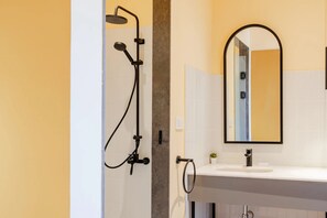 A bathroom with a shower, sink, mirror, and tiled walls. - Studio Apartments Downtown Alexandria Menascehouse (Alexandria)