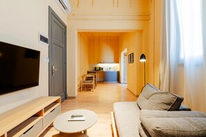 A modern living room with a flat-screen TV, a sofa, a coffee table, and a kitchen area in the background. - Studio Apartments Downtown Alexandria Menascehouse (Alexandria)