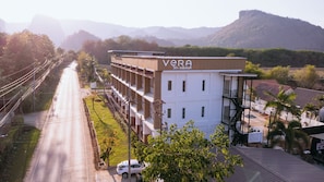 A multi-story building with a sign reading 'VERA' and a view of a road with a car parked in front. - Vera Residecnes (Mae Sai)