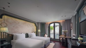 A hotel room with two beds, a desk, a chair, a TV, and a balcony with curtains. - Tonkin Luxury Boutique Hotel & Spa (Hanoi)