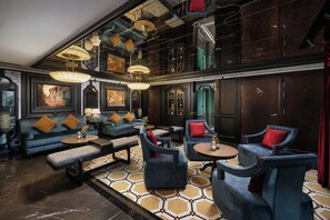 Un salon spacieux avec un plafond haut, de nombreux coins salon et des œuvres d’art accrochées aux murs.