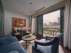 Una habitación con balcón, sofá, mesa con sillas y un cuadro en la pared.