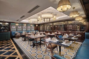 A restaurant with a patterned floor, wooden furniture, and hanging chandeliers. - Tonkin Luxury Boutique Hotel & Spa (Hanoi)