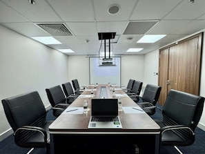 A conference room with a long table, black chairs, a laptop, water bottles, and a projector screen. - Tonkin Luxury Boutique Hotel & Spa (Hanoi)