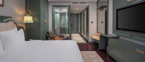 Una habitación de hotel con una cama grande, televisión, escritorio y una silla.