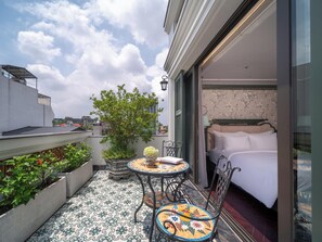 Un balcon avec un lit, une table et des chaises. On y trouve également un arbre et une plante en pot.