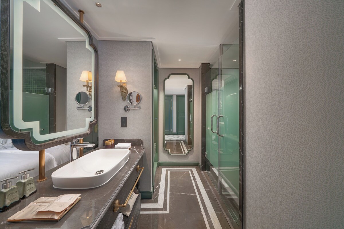 A modern bathroom with a large mirror, a sink, and a shower.