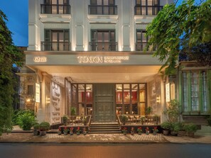 Fachada imponente de un hotel de lujo, con iluminación destacada y plantas en macetas.