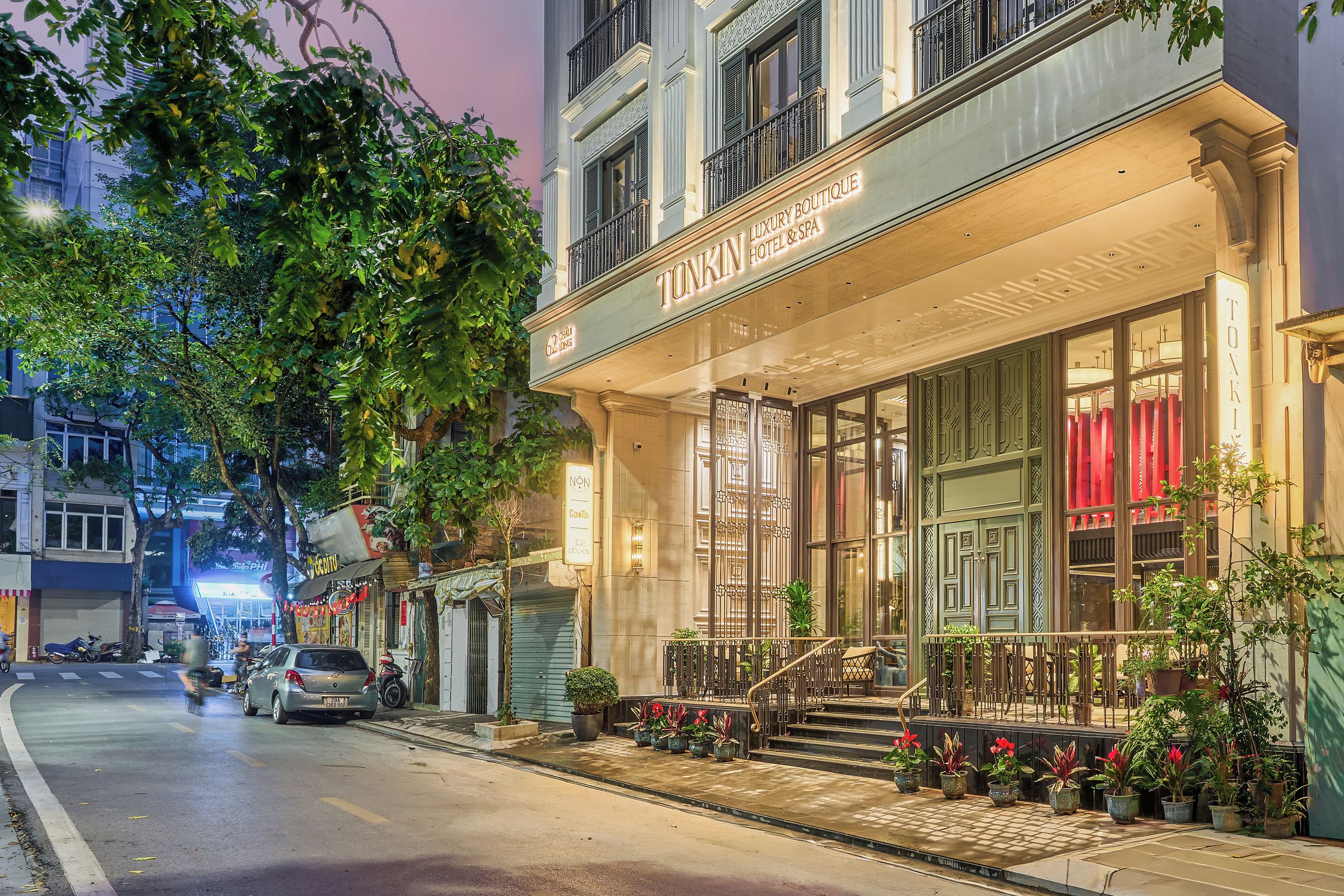 A luxury boutique hotel with a grand entrance, a staircase, and potted plants.