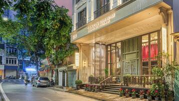 A luxury boutique hotel with a grand entrance, a staircase, and potted plants.
