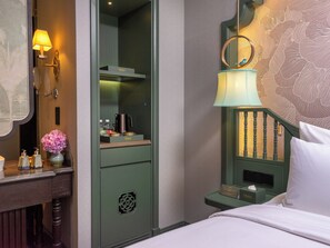Una habitación de hotel con una cama, una mesita de noche con lámpara, un espejo, un aparador y una pequeña mesa con artículos de aseo.